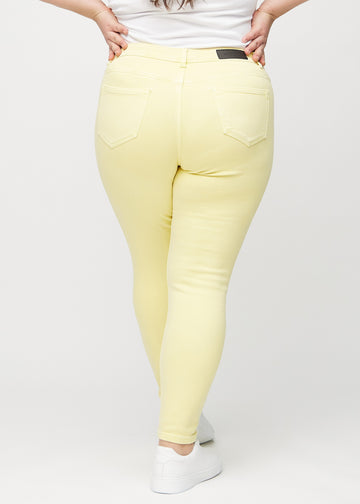 Hellgelbe skinny jeans von hinten an einem Plus-Size-Model gesehen, damit man das ganze Produkt sehen kann.