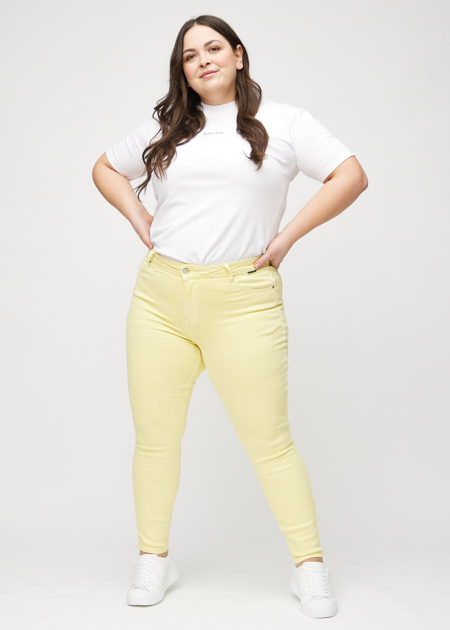 Ganzkörperbild eines Plus-Size-Models in hellgelben skinny jeans.