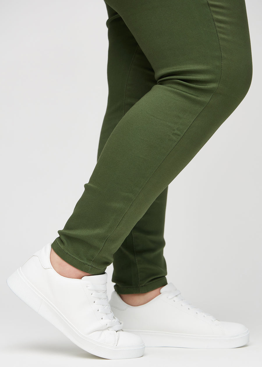 Skinny-Jeans für Damen in Dunkelgrün, Farbe Renewals. Nahaufnahme der eng anliegenden Beinabschlüsse am Knöchel eines Plus-Size-Models.