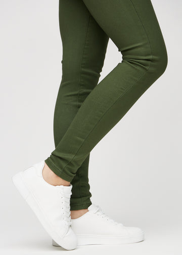 Skinny-Jeans für Damen in Dunkelgrün, Farbe Renewals. Nahaufnahme am Knöchel eines Models, die eng anliegenden Beinabschlüsse sind zu sehen.