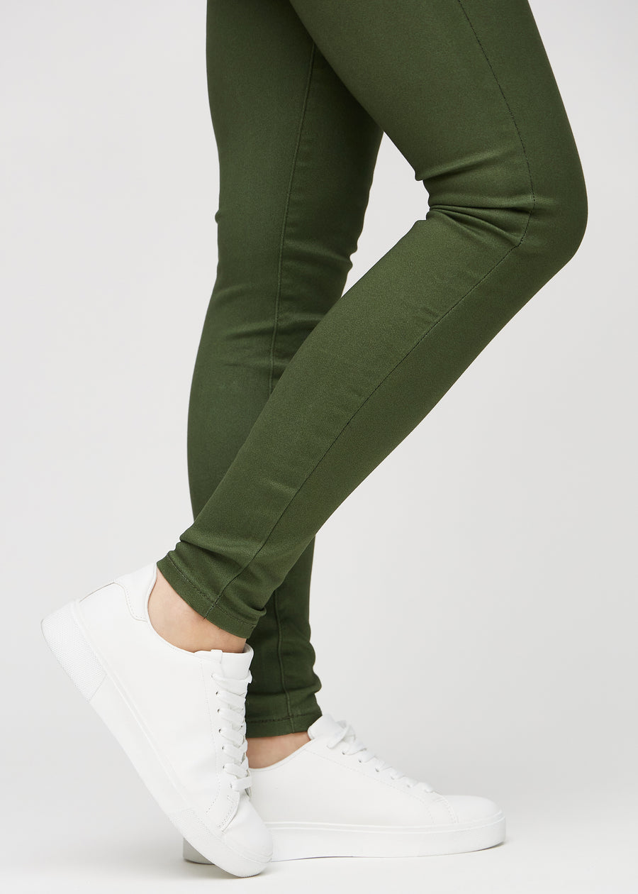 Skinny-Jeans für Damen in Dunkelgrün, Farbe Renewals. Nahaufnahme am Knöchel eines Models, die eng anliegenden Beinabschlüsse sind zu sehen.