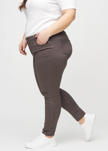 Graubraune skinny jeans von der Seite an einem Plus-Size-Model gezeigt.