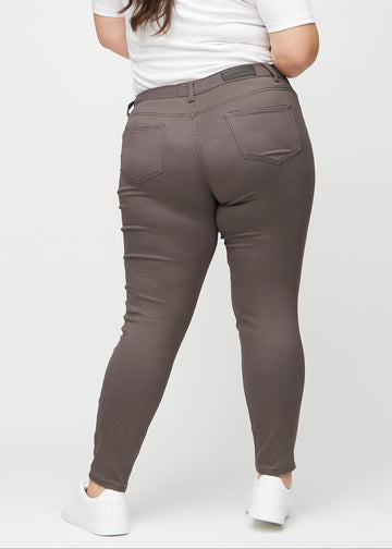 Graubraune skinny jeans von hinten an einem Plus-Size-Model gesehen, damit man das gesamte Produkt sehen kann.