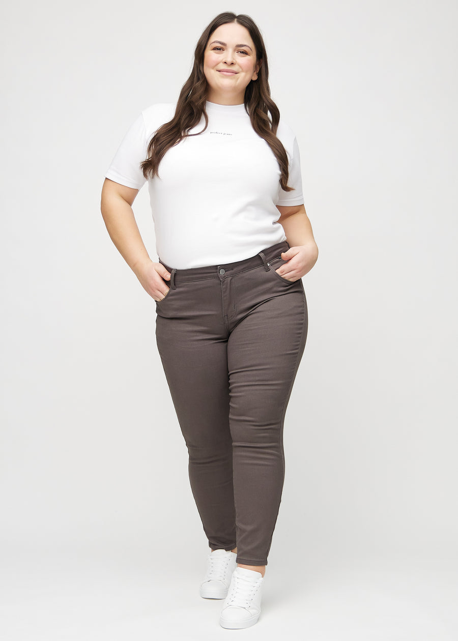 Ganzkörperbild eines Plus-Size-Models in graubraunen skinny jeans.