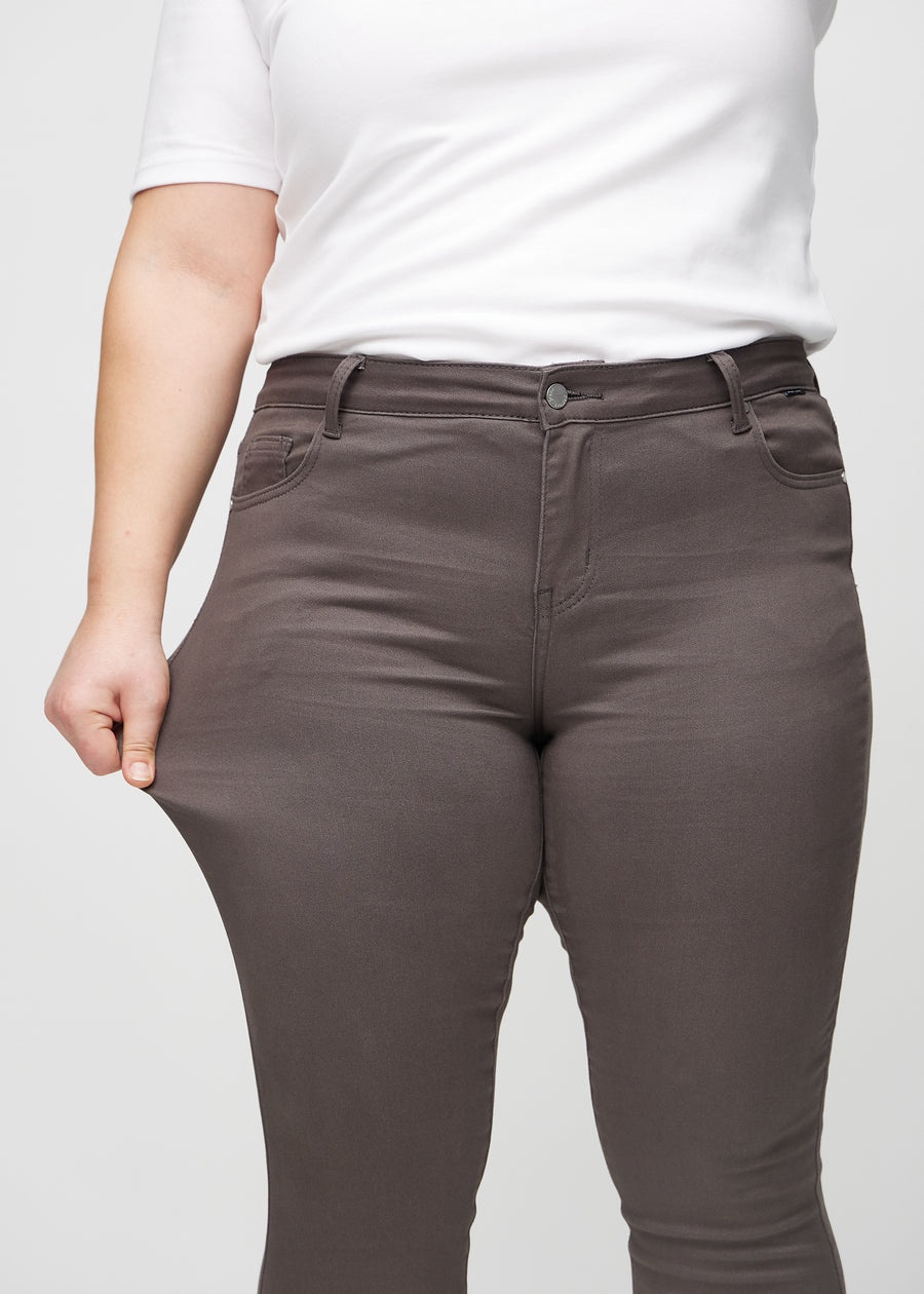 Das Plus-Size-Model dehnt die Jeans am Oberschenkel, um den Stretch zu zeigen.