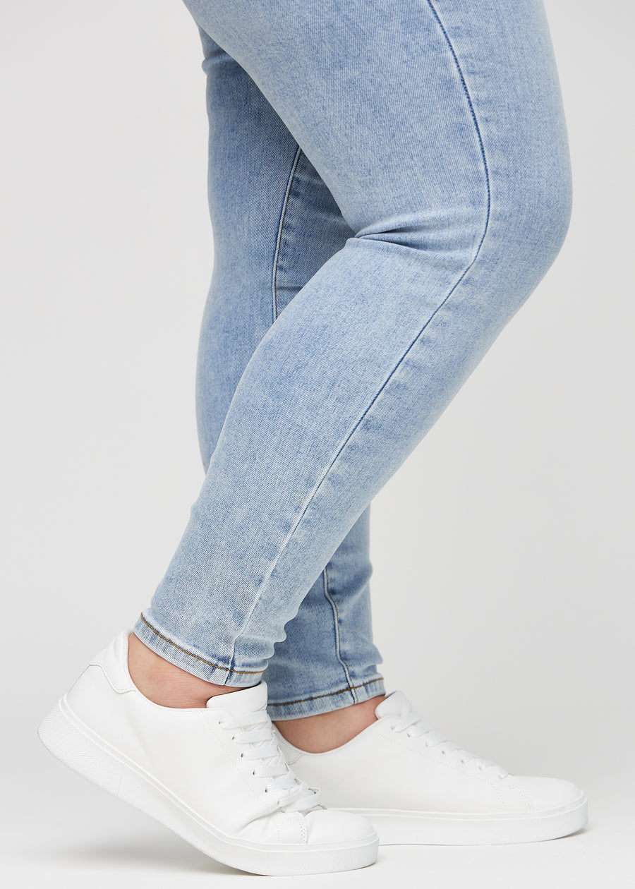 Skinny-Jeans für Damen in Hellblau, Farbe Waves. Nahaufnahme der eng anliegenden Beinabschlüsse am Knöchel eines Plus-Size-Models.