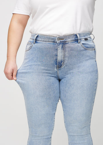Skinny-Jeans für Damen in Hellblau, Farbe Waves. Ein Plus-Size-Model dehnt den Jeansstoff am Oberschenkel, um den Stretch zu zeigen.