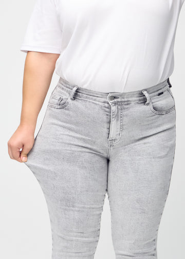 Das Plus-Size-Model zieht die Jeans am Oberschenkel auseinander, um den Stretch zu zeigen.