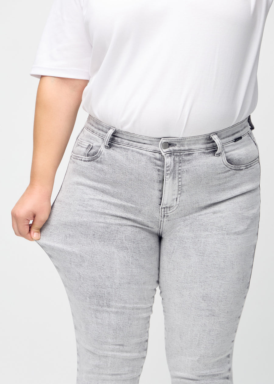 Das Plus-Size-Model zieht die Jeans am Oberschenkel auseinander, um den Stretch zu zeigen.