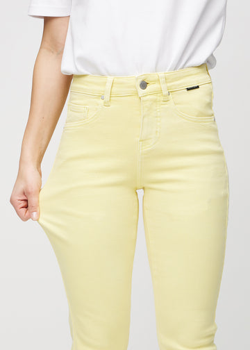 Slim-Jeans für Damen in Hellgelb, Farbe Lemonades. Ein Model zieht am Jeansstoff am Oberschenkel, um den Stretch zu zeigen.