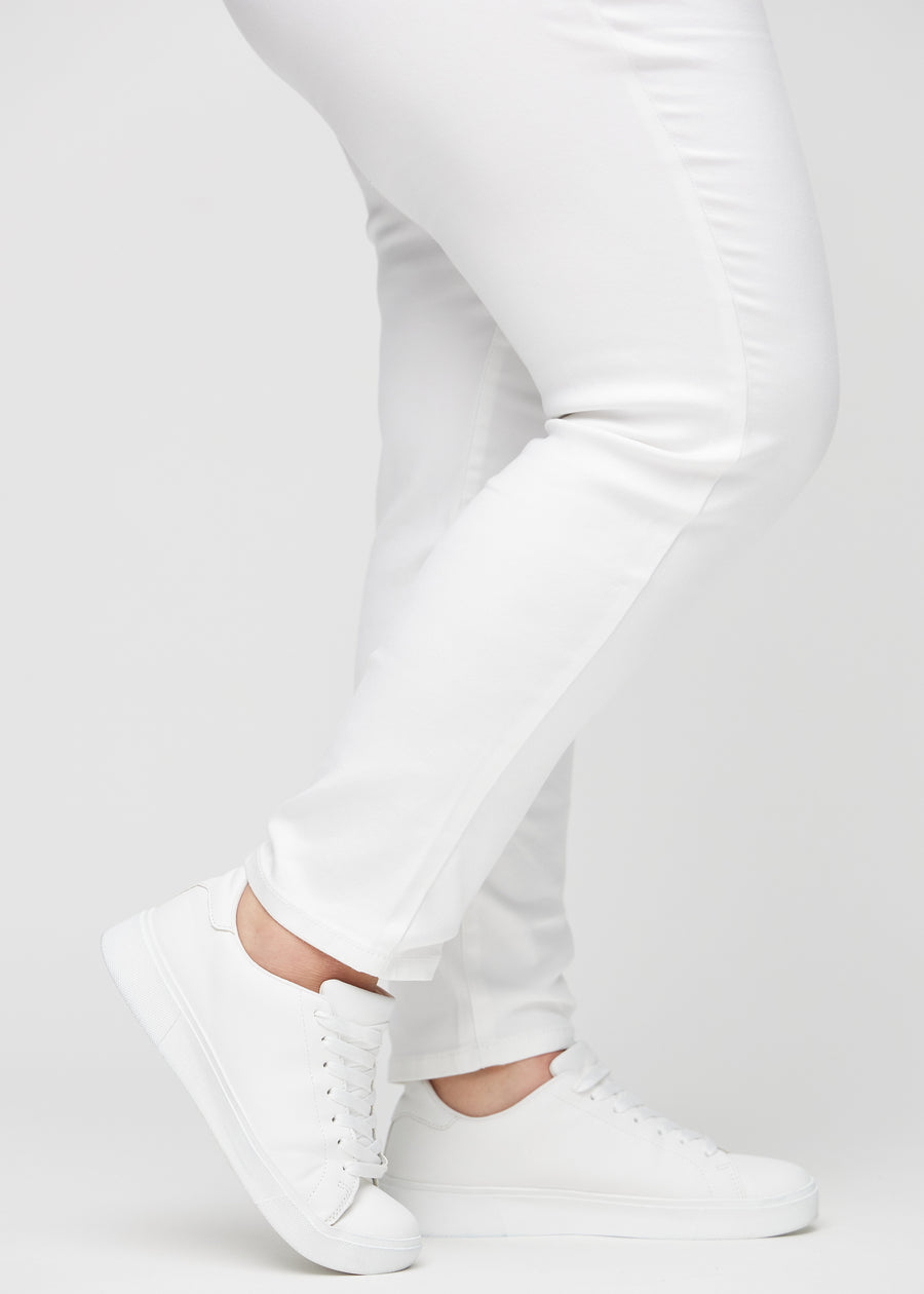 Slim-Jeans für Damen in Weiß, Farbe Marguerites. Nahaufnahme an den Knöcheln eines Plus-Size-Models, um die Passform am Beinabschluss zu zeigen.