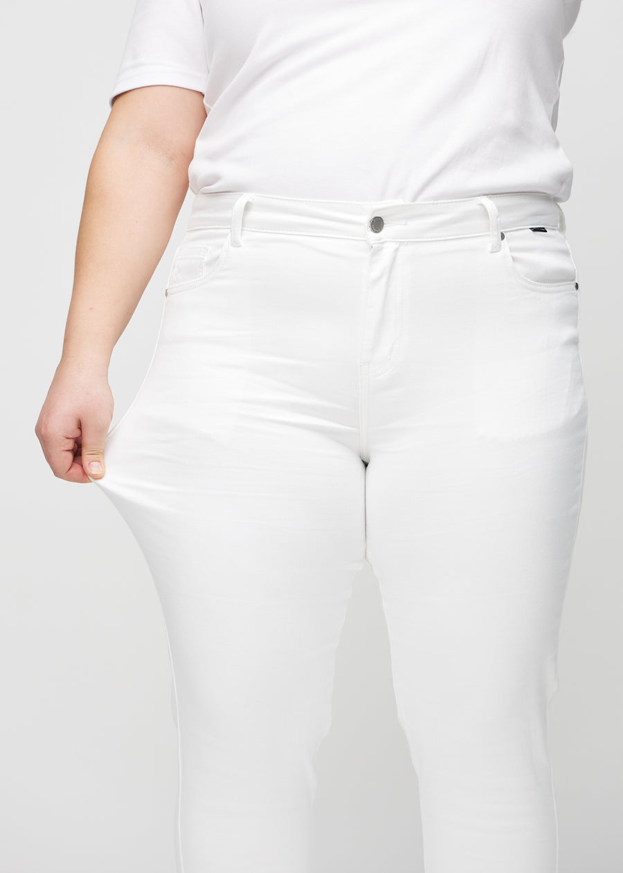 Slim-Jeans für Damen in Weiß, Farbe Marguerites. Ein Plus-Size-Model zieht am Jeansstoff am Oberschenkel, um den Stretch zu zeigen.