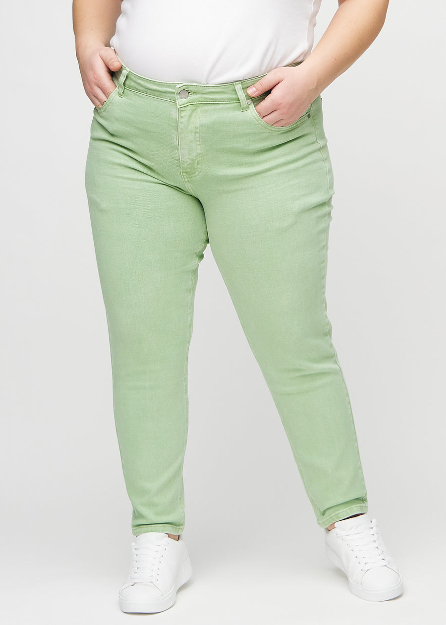 Hellgrüne slim jeans, Modellname Mints, die eng am Bein anliegen, jedoch am Knöchel etwas lockerer sind, an einem Plus-Size-Model, von vorne gesehen.