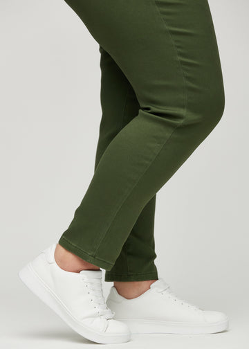 Slim-Jeans für Damen in Dunkelgrün, Farbe Renewals. Nahaufnahme an den Knöcheln eines Plus-Size-Models, um die Passform am Beinabschluss zu zeigen.