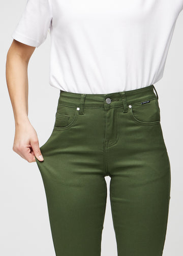 Slim-Jeans für Damen in Dunkelgrün, Farbe Renewals. Ein Model zieht am Jeansstoff am Oberschenkel, um den Stretch zu zeigen.