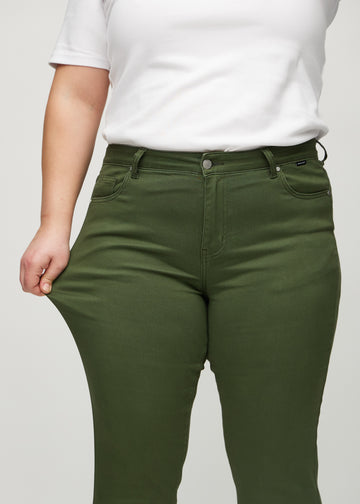Slim-Jeans für Damen in Dunkelgrün, Farbe Renewals. Ein Plus-Size-Model zieht am Jeansstoff am Oberschenkel, um den Stretch zu zeigen.