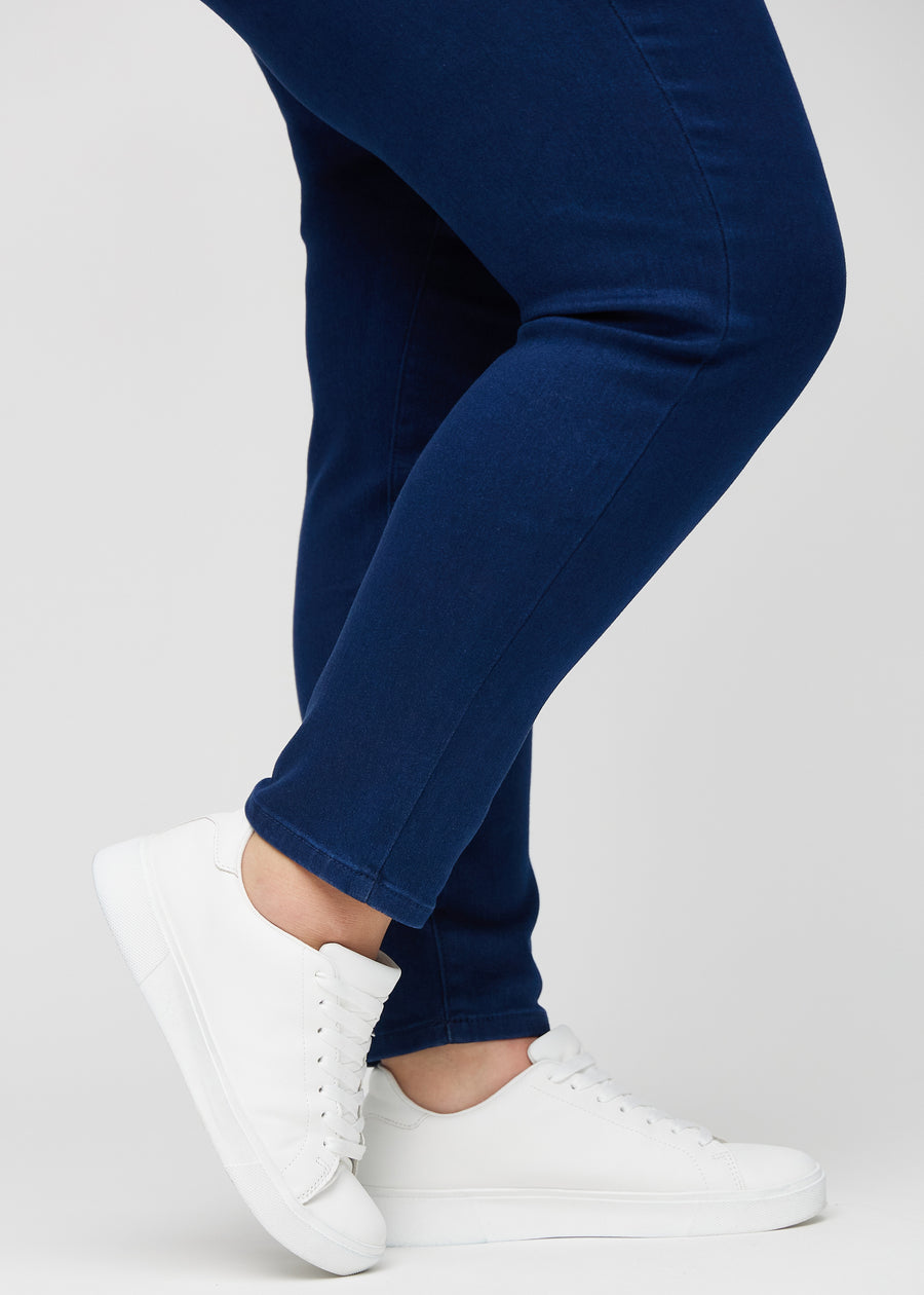 Slim-Jeans für Damen in Dunkelblau, Farbe Royals. Nahaufnahme an den Knöcheln eines Plus-Size-Models, um die Passform am Beinabschluss zu zeigen.