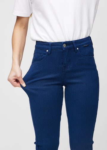 Slim-Jeans für Damen in Dunkelblau, Farbe Royals. Ein Model zieht am Jeansstoff am Oberschenkel, um den Stretch zu zeigen.