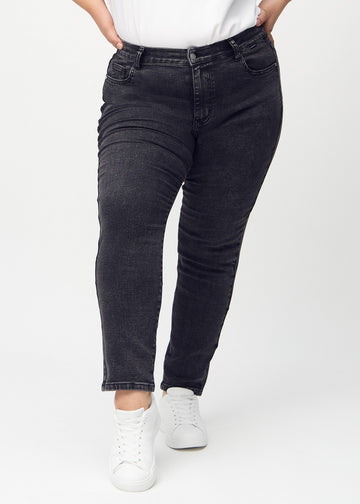 Dunkelgrauer Denim slim jeans, Modellname Shadows, der eng am Bein anliegt, jedoch am Knöchel etwas lockerer sitzt, an einem Plus-Size-Model, von vorne gesehen.