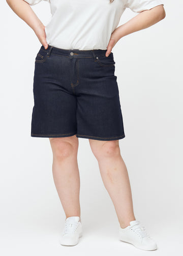 Tief dunkelblaue Denim-Shorts für Damen in der Farbe Midnights mit Loose-Passform, von vorne auf einem Plus-Size-Model gesehen.
