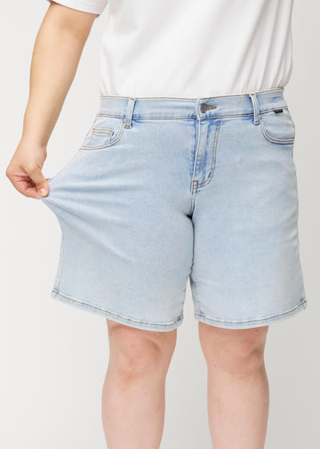 Ein weibliches Model dehnt die hellblauen Waves Denim-Shorts am Oberschenkel, um den Stretch des Materials zu zeigen.