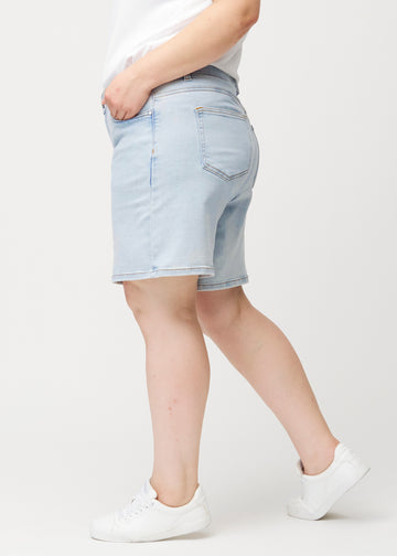 Seitenansicht eines weiblichen Models in hellblauen Waves Denim-Shorts mit mittelhohem Bund (Mid Rise) und Loose Fit.