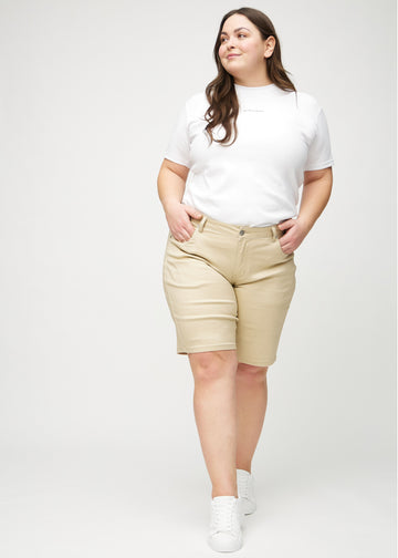 Ganzkörperbild eines Plus-Size-Models in beige regular middle shorts.