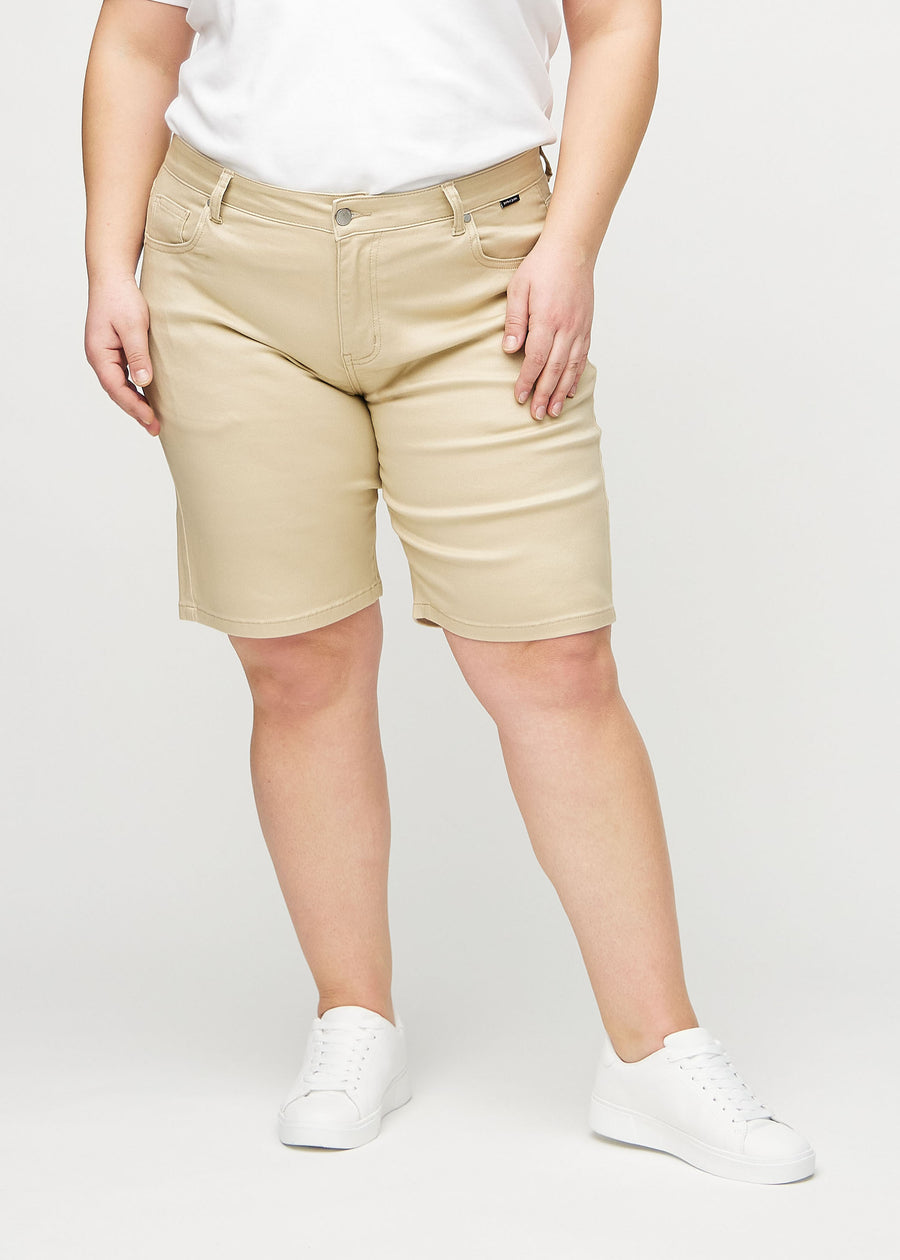 Beige regular middle shorts, Modellname Gazelles, die gerade am Bein entlang fallen und knapp über dem Knie enden, an einem Plus-Size-Model von vorne gesehen.