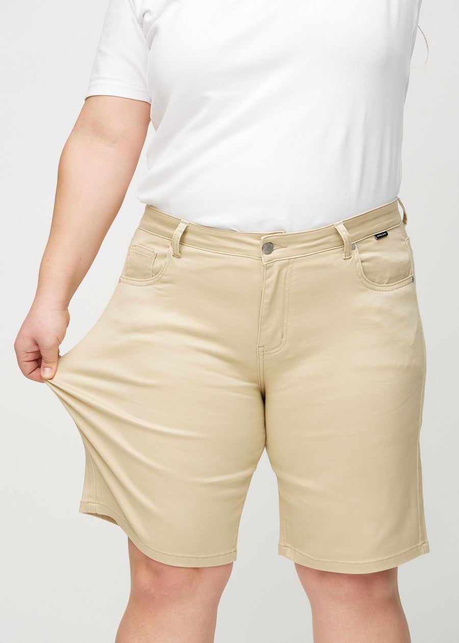 Das Plus-Size-Model zieht die Shorts am Oberschenkel auseinander, um den Stretch zu zeigen.