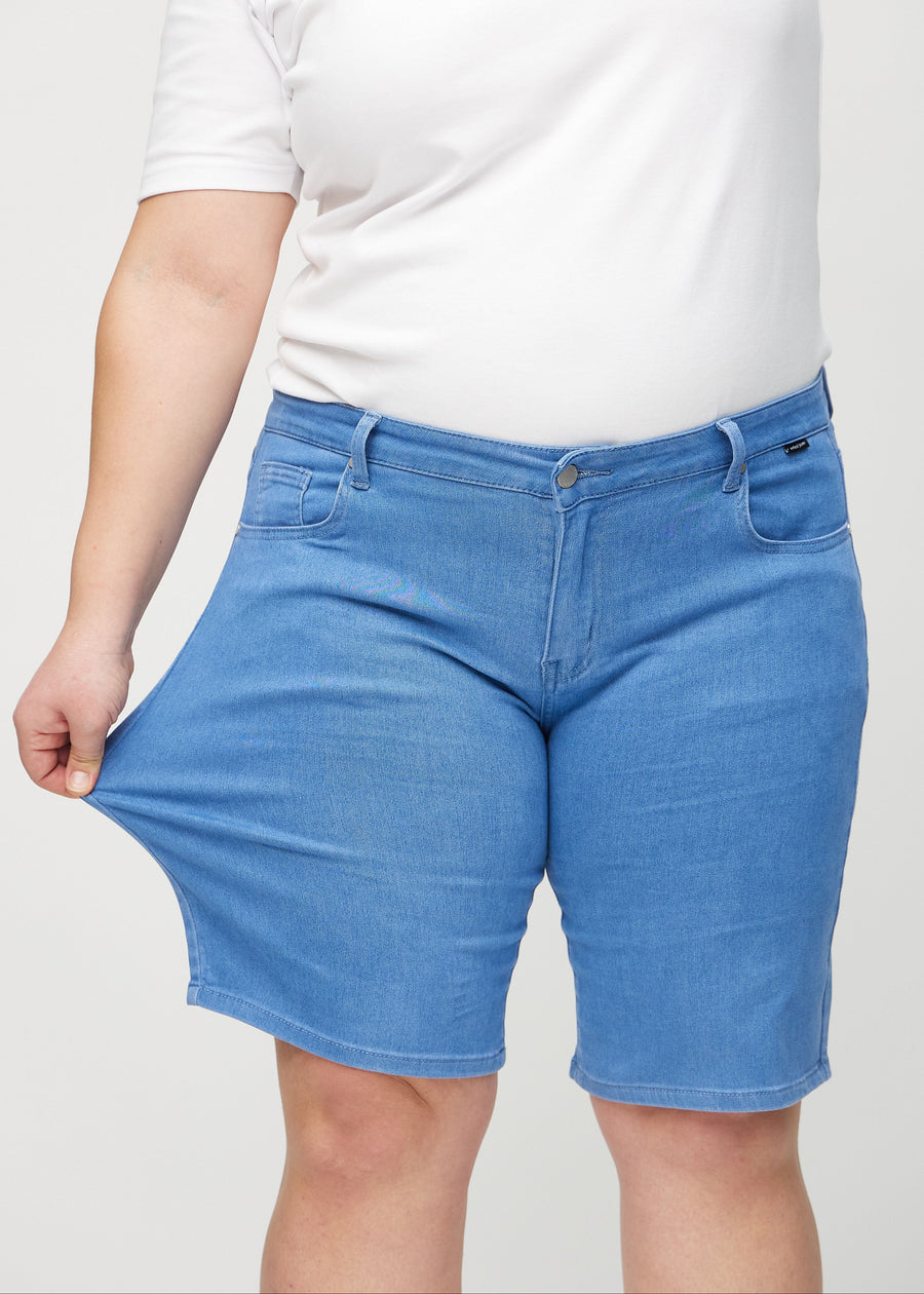 Das Plus-Size-Model zieht die Shorts am Oberschenkel auseinander, um den Stretch zu zeigen.