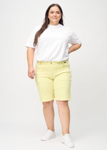 Ganzkörperbild eines Plus-Size-Models in hellgelben regular Middle Shorts.