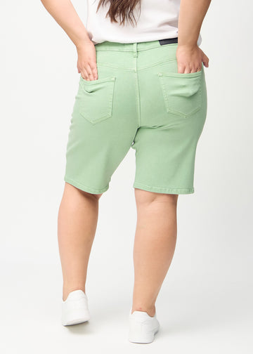 Hellgrüne regular middle shorts von hinten an einem Plus-Size-Model gesehen, sodass man das gesamte Produkt sehen kann.