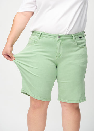 Das Plus-Size-Model zieht die Shorts am Oberschenkel auseinander, um den Stretch zu zeigen.