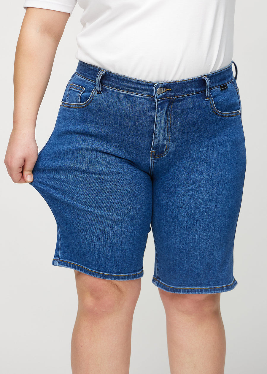 Das Plus-Size-Model zieht die Shorts am Oberschenkel auseinander, um den Stretch zu zeigen.