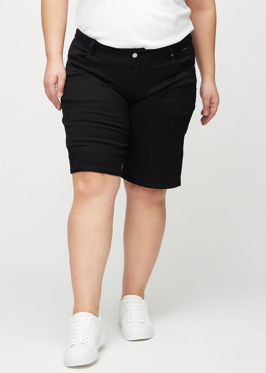 Schwarze regular Middle Shorts, Modellname Ravens, die gerade am Bein herunterfallen und knapp über dem Knie enden, an einem Plus-Size-Model, von vorn gesehen.