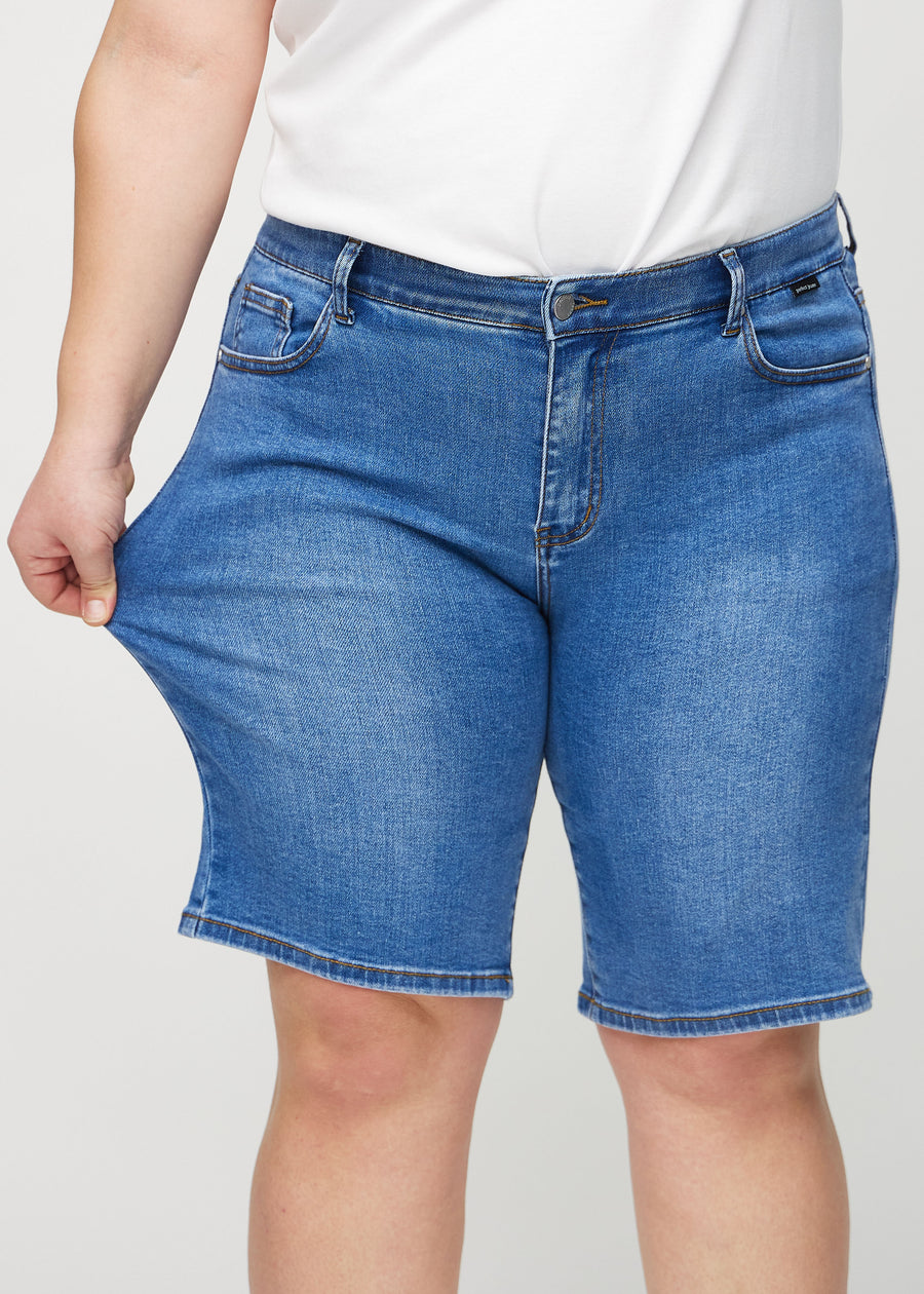 Das Plus-Size-Model zieht die Shorts am Oberschenkel auseinander, um den Stretch zu zeigen.