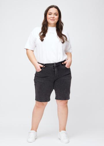 Ganzkörperbild eines Plus-Size-Models in dunkelgrauen Denim-regular-Middle-Shorts.