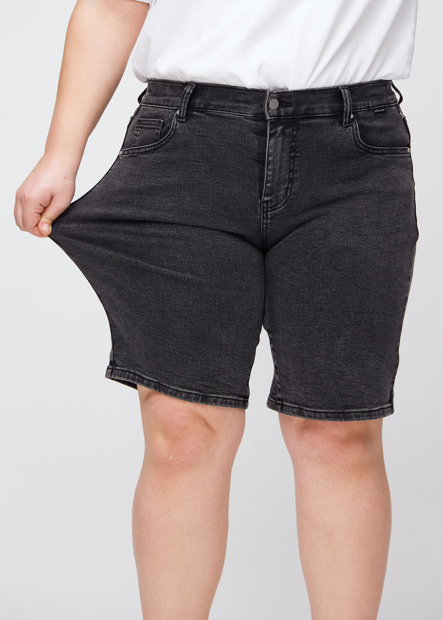 Plus-Size-Model dehnt die Shorts am Oberschenkel, um den Stretch zu zeigen.