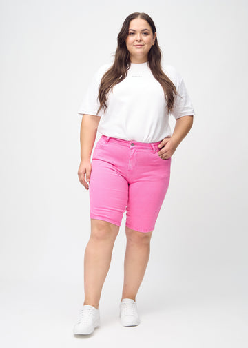 Ganzkörperbild eines Plus-Size-Models in hellrosa skinny middle shorts.