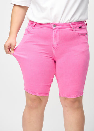 Das Plus-Size-Model zieht die Shorts am Oberschenkel auseinander, um den Stretch zu zeigen.