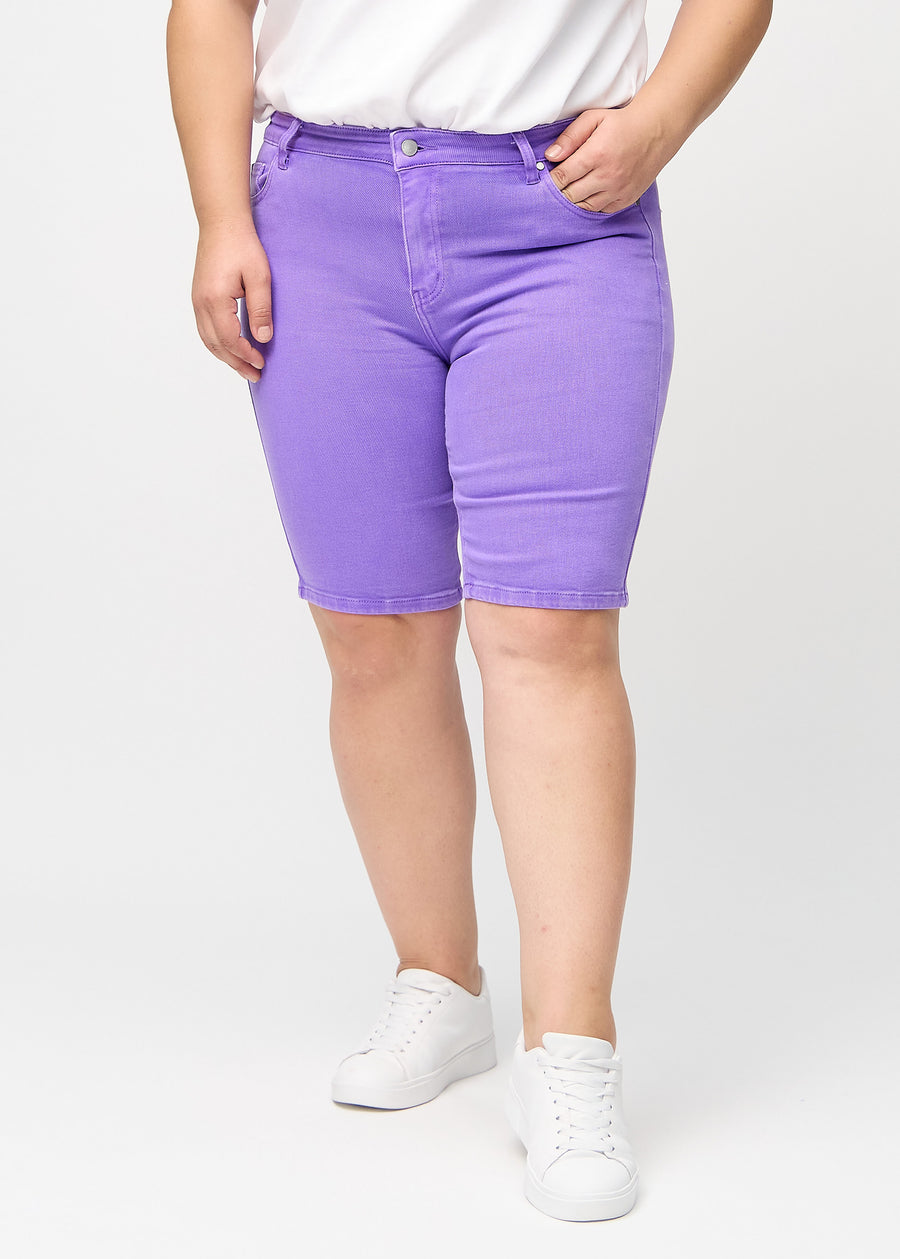 Lila skinny middle shorts, Modellname Lavenders, die eng am Oberschenkel anliegen und bei einem Plus-Size-Model knapp über dem Knie enden, von vorn gesehen.