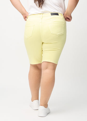 Hellgelbe skinny middle shorts von hinten an einem Plus-Size-Model gesehen, sodass man das gesamte Produkt sehen kann.