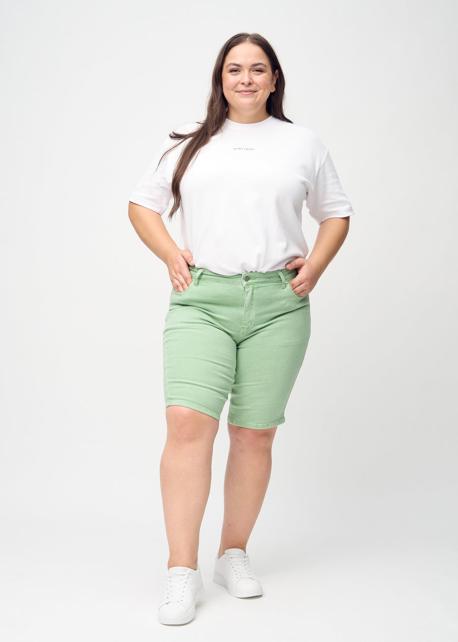Ganzkörperbild eines Plus-Size-Models in hellgrünen skinny middle shorts.