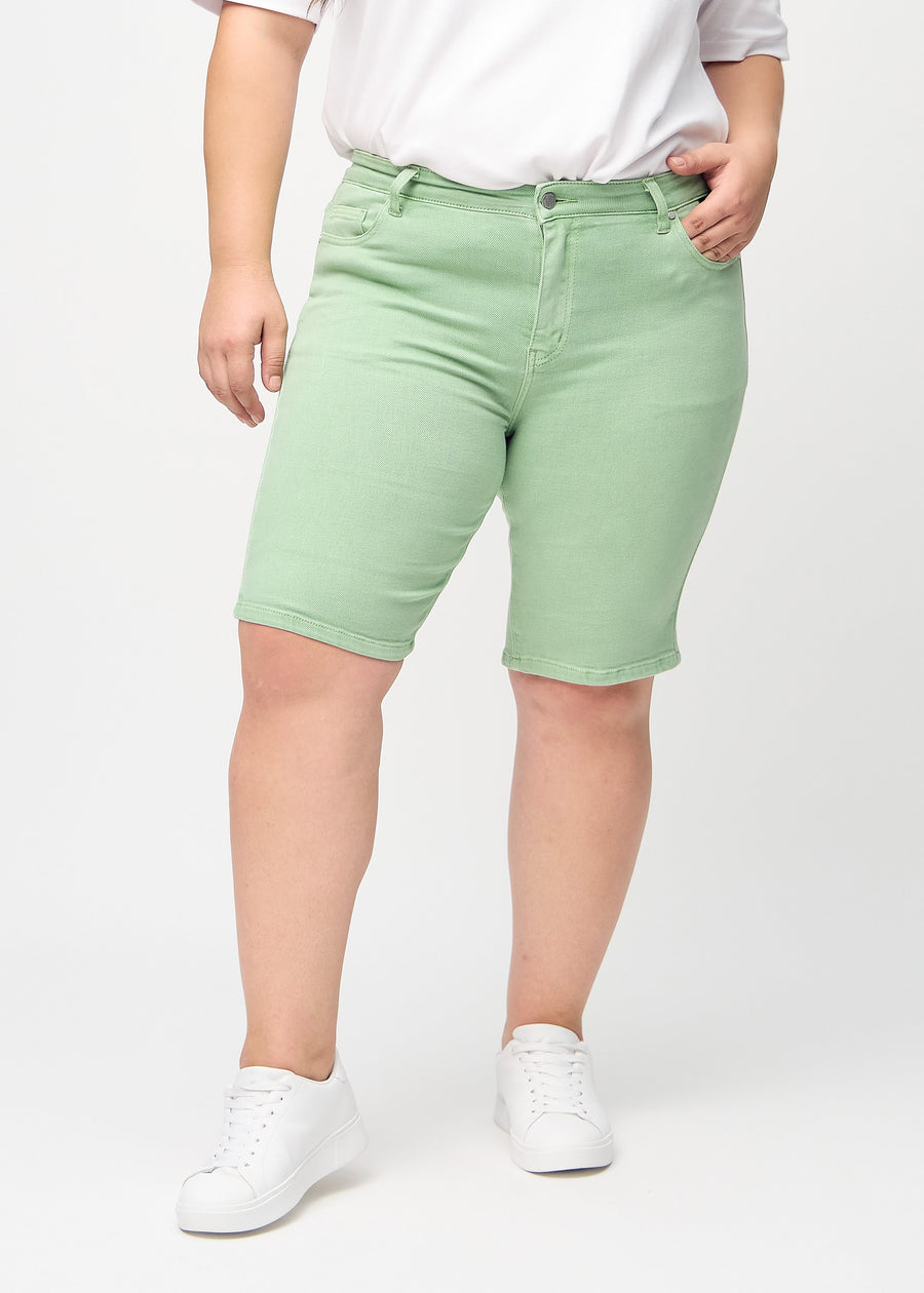 Hellgrüne skinny middle shorts, Modellname Mints, die eng am Oberschenkel anliegen und knapp über dem Knie enden, an einem Plus-Size-Model von vorne gesehen.