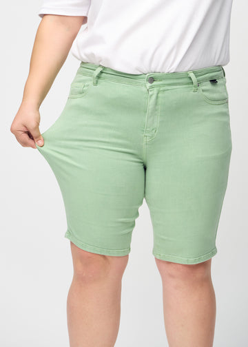 Das Plus-Size-Model zieht die Shorts am Oberschenkel, um den Stretch zu zeigen.