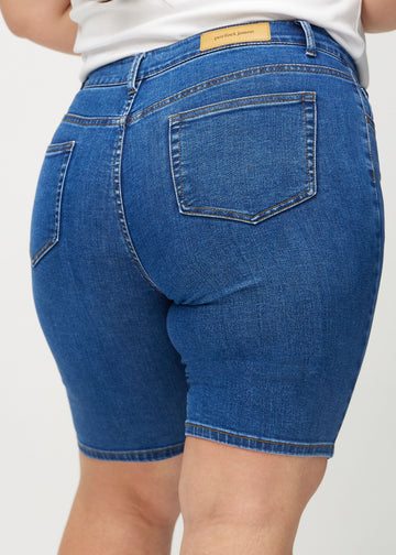 Dunkle Denim-skinny middle shorts von hinten in Nahaufnahme an einem Plus-Size-Model, um Details zu zeigen.