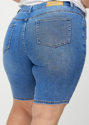 Denim skinny middle shorts von hinten in Nahaufnahme an einem Plus-Size-Model, um Details zu zeigen.