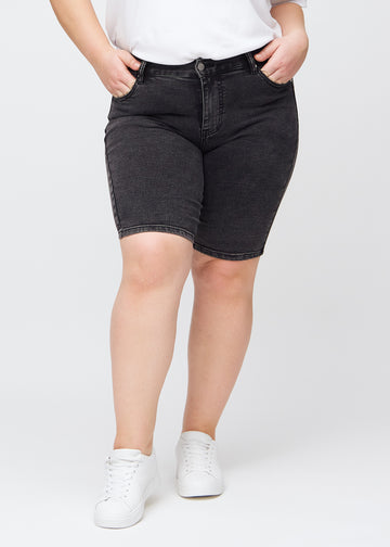Dunkelgraue Denim-skinny-Middle-Shorts, Modellname Shadows, die eng am Oberschenkel anliegen und bei einem Plus-Size-Model knapp über dem Knie enden, von vorn gesehen.