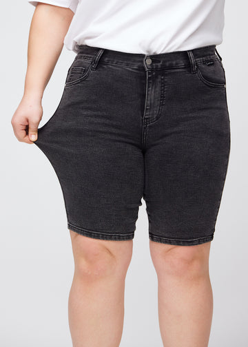Das Plus-Size-Model zieht die Shorts am Oberschenkel auseinander, um den Stretch zu zeigen.