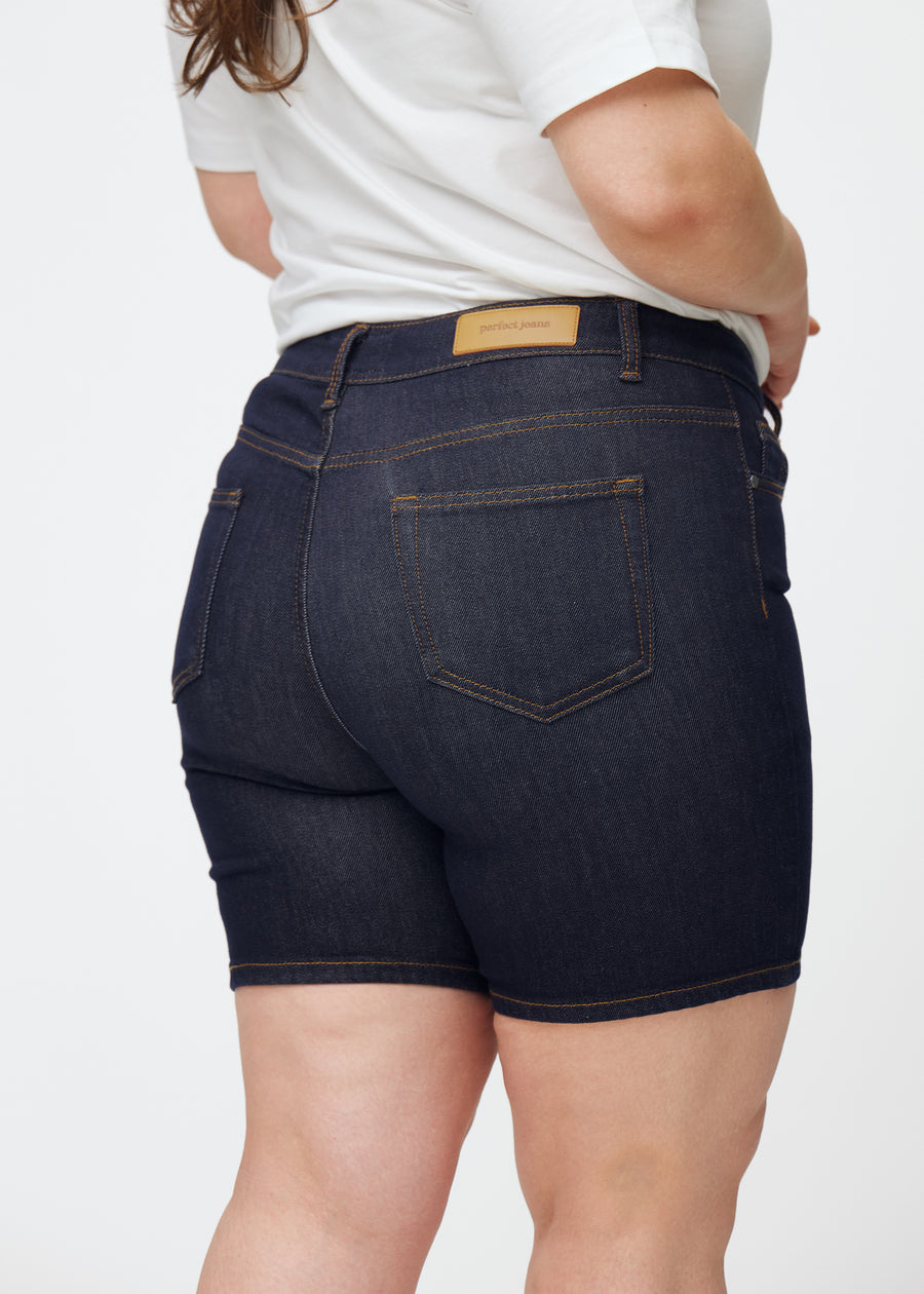 Tief dunkelblaue Denim-Shorts für Damen in der Farbe Midnights von hinten nah auf einem Plus-Size-Model aufgenommen, um Passform und Details zu zeigen.